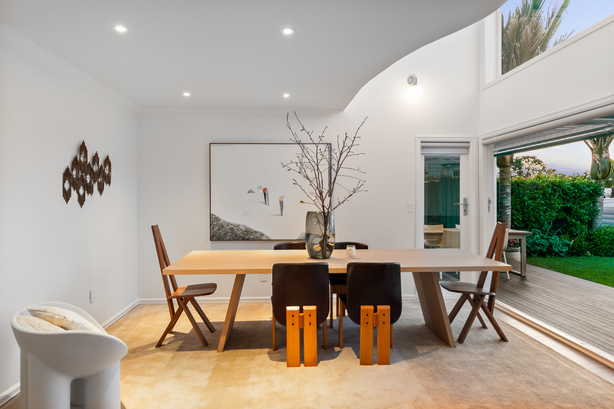 Contemporary dining area arranged beneath a curved ceiling and opening to the garden