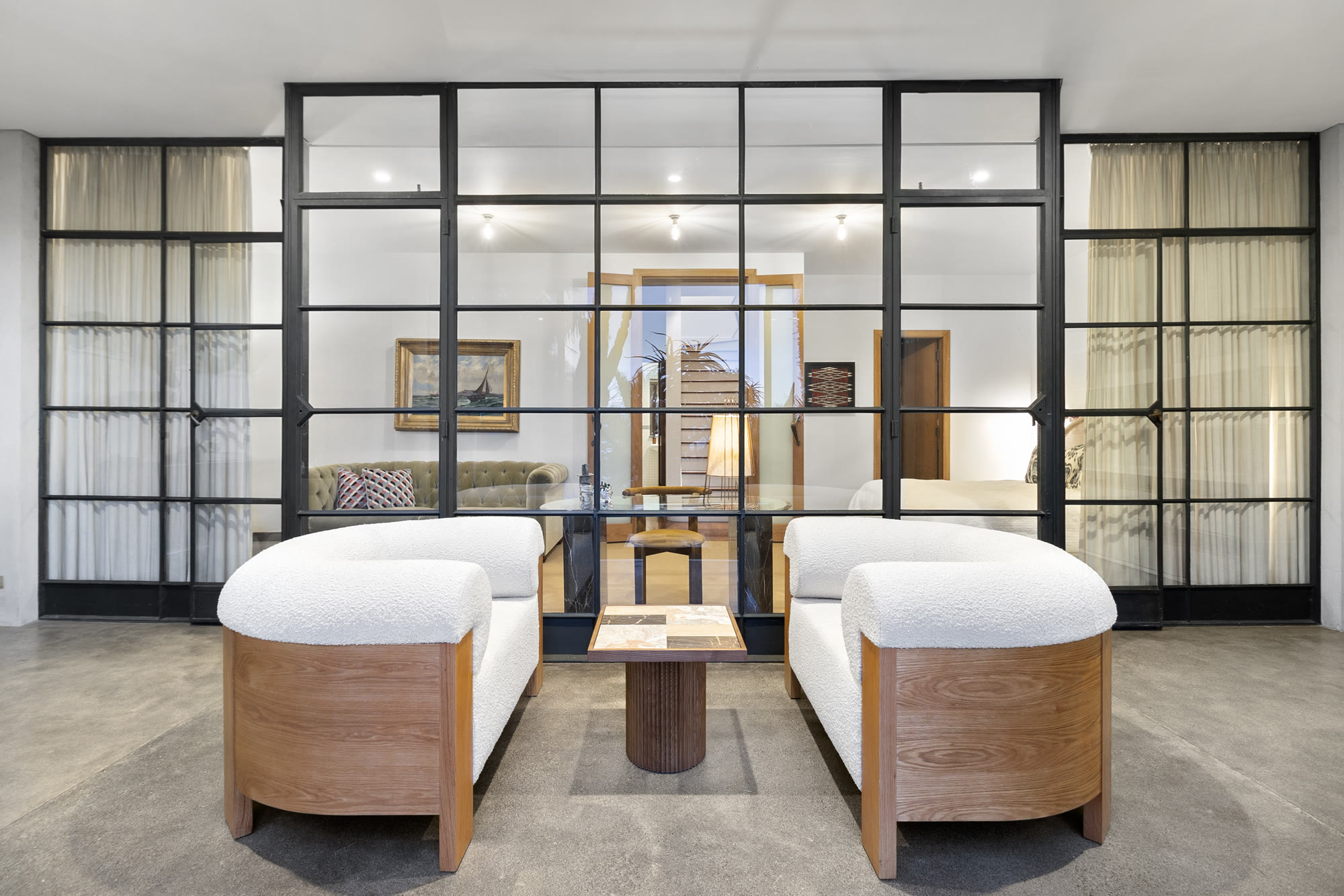 Completed lounge installation with sculptural seating framed by black steel glazing