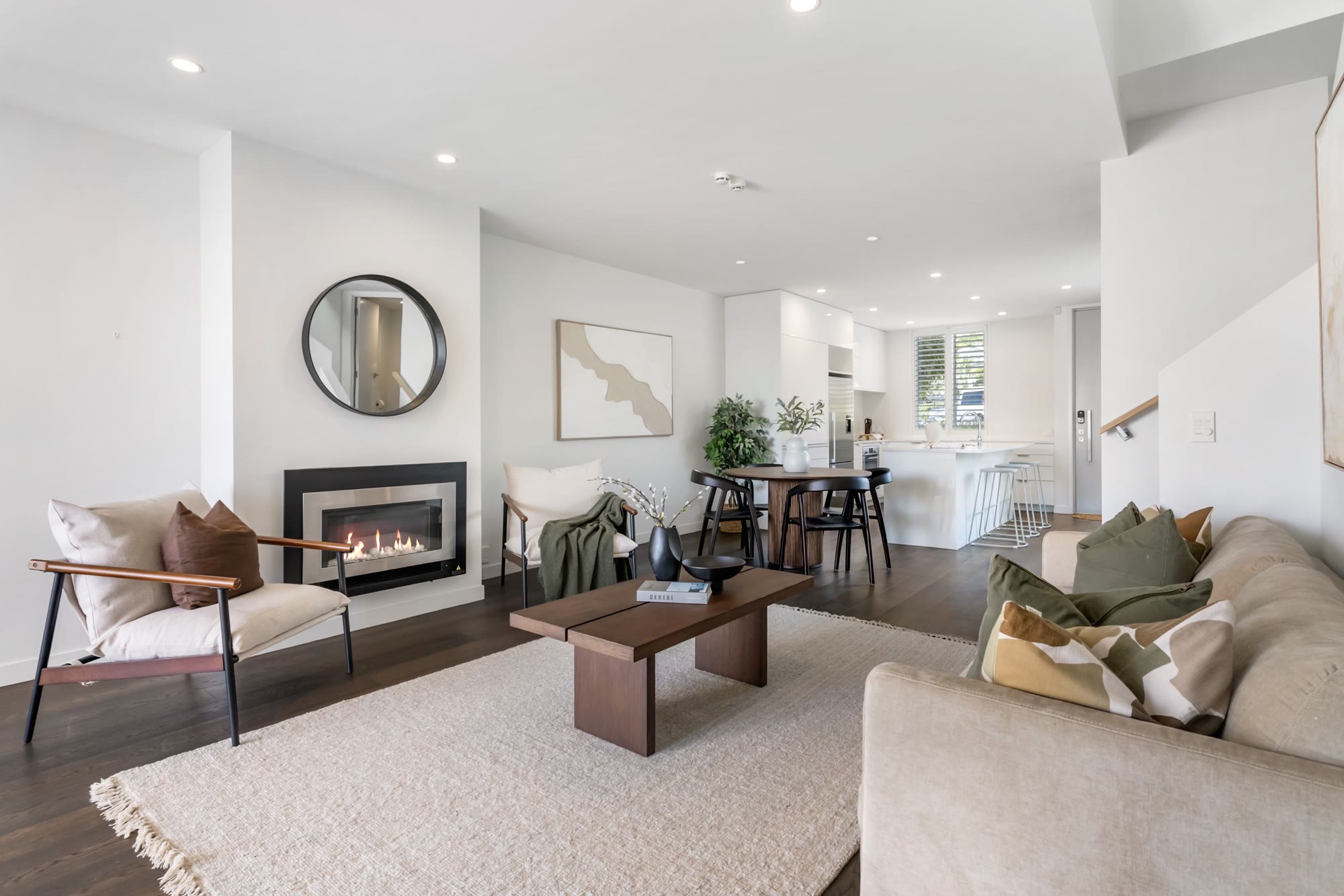 Complete living and dining scheme with neutral furniture, timber accents and a bright kitchen beyond