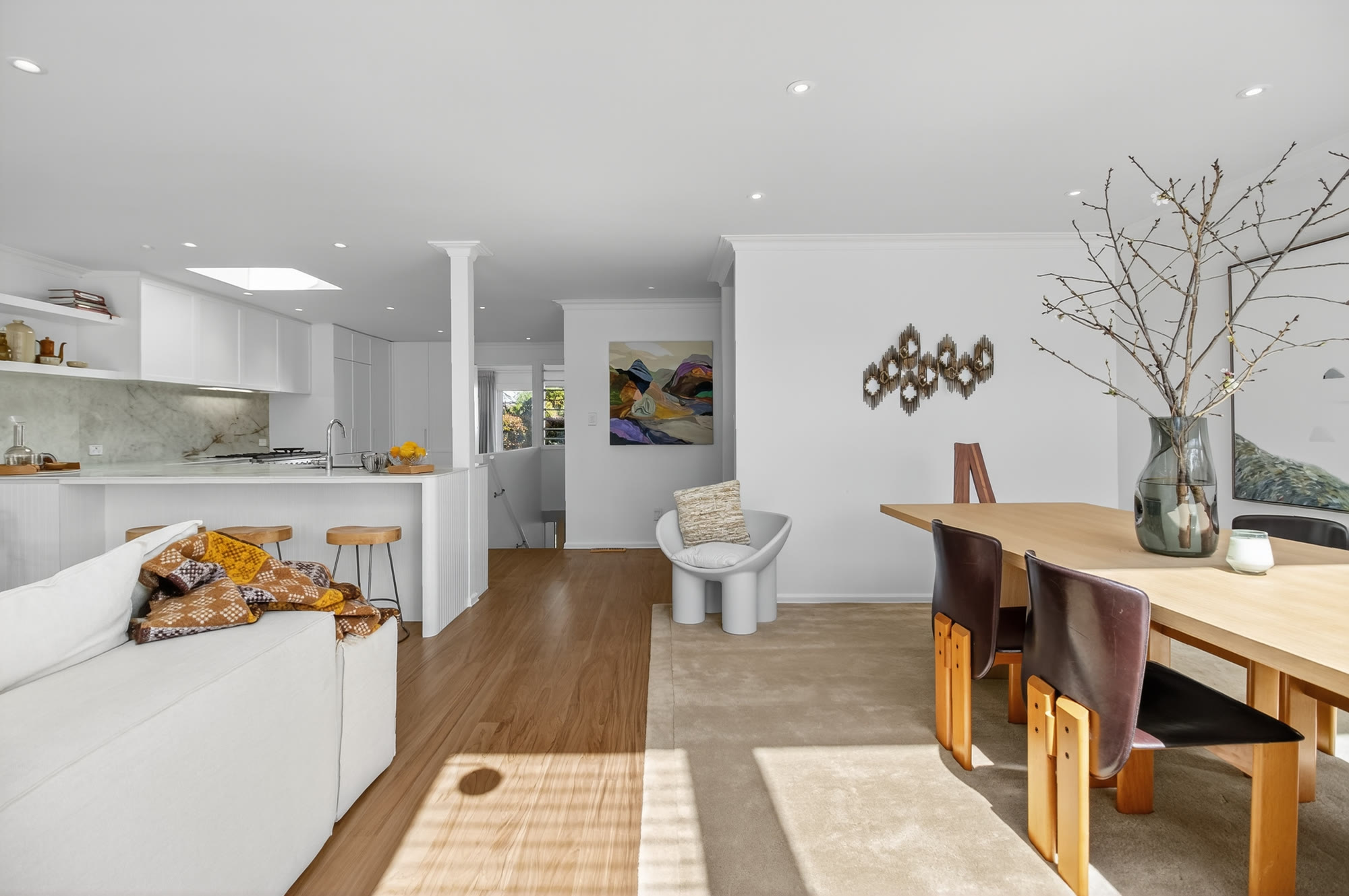 Open-plan living, dining and kitchen scheme with neutral seating and black cabinetry