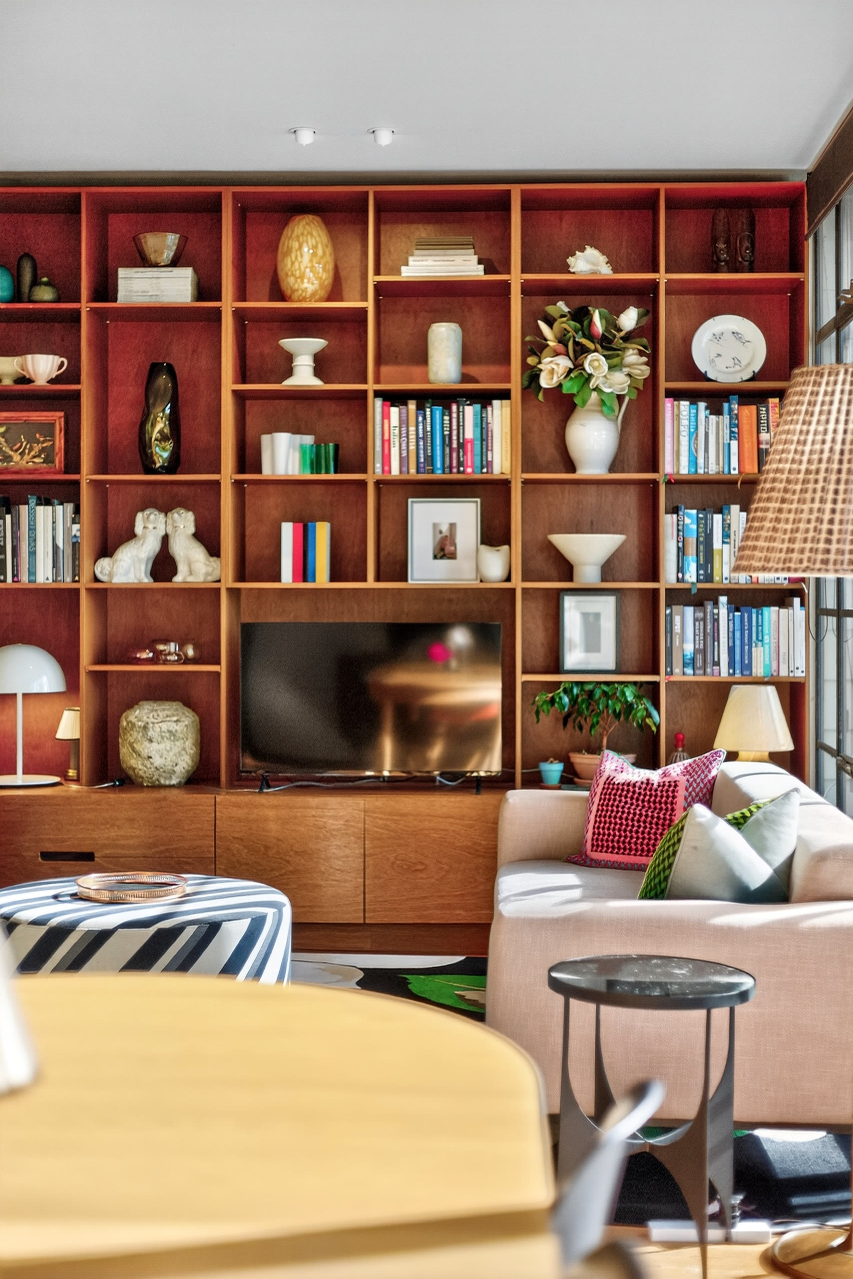Neutral sofa layered with cushions, greenery and a dark coffee table