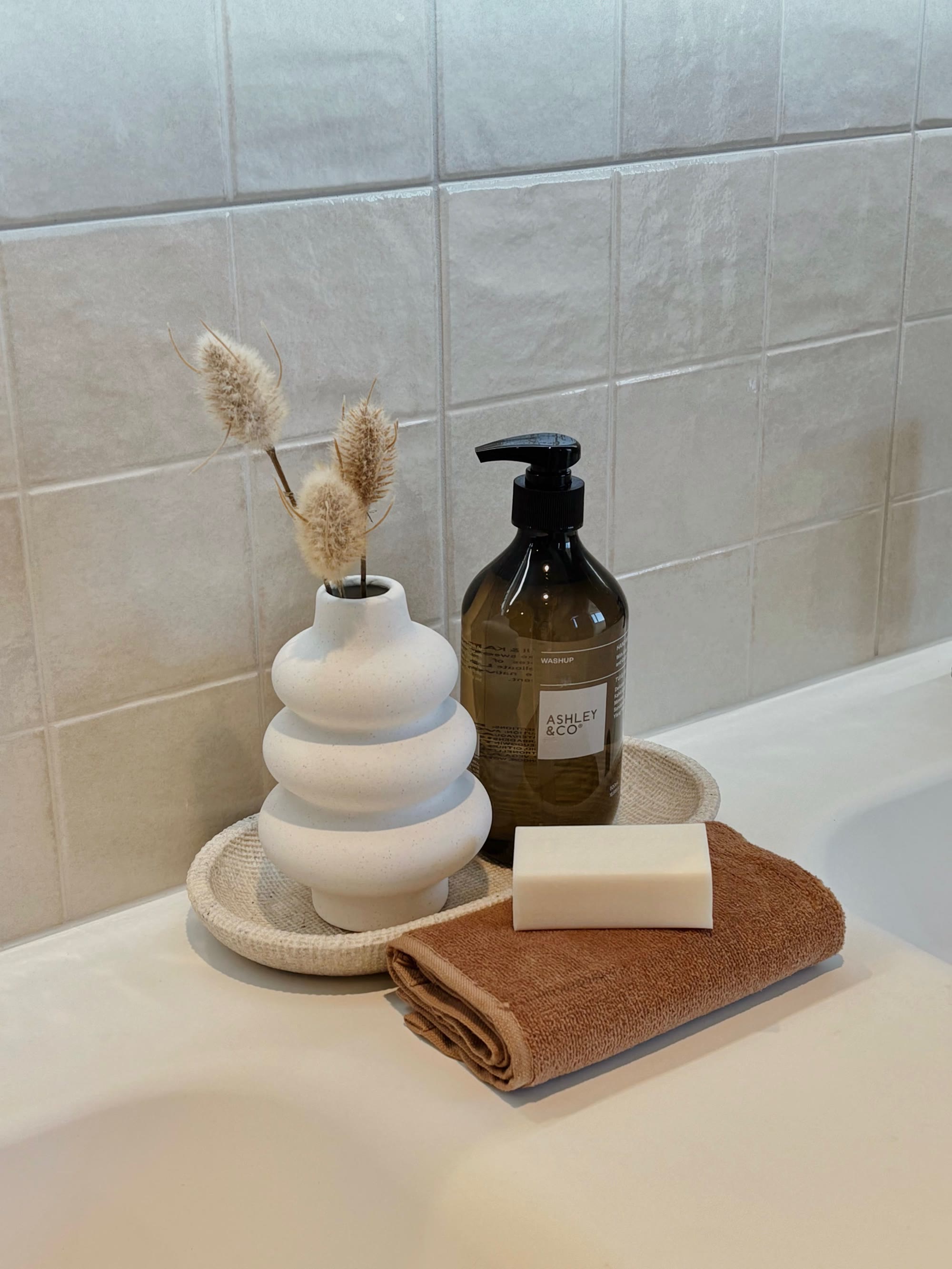 Bathroom styling with a sculptural vase, amber hand wash, soap and a rust towel