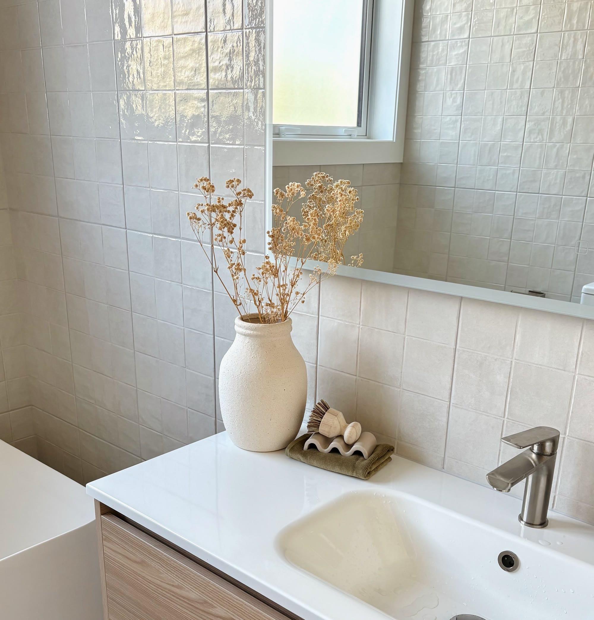 Light tiled bathroom vanity styled with a ceramic vase, dried flowers and natural accessories
