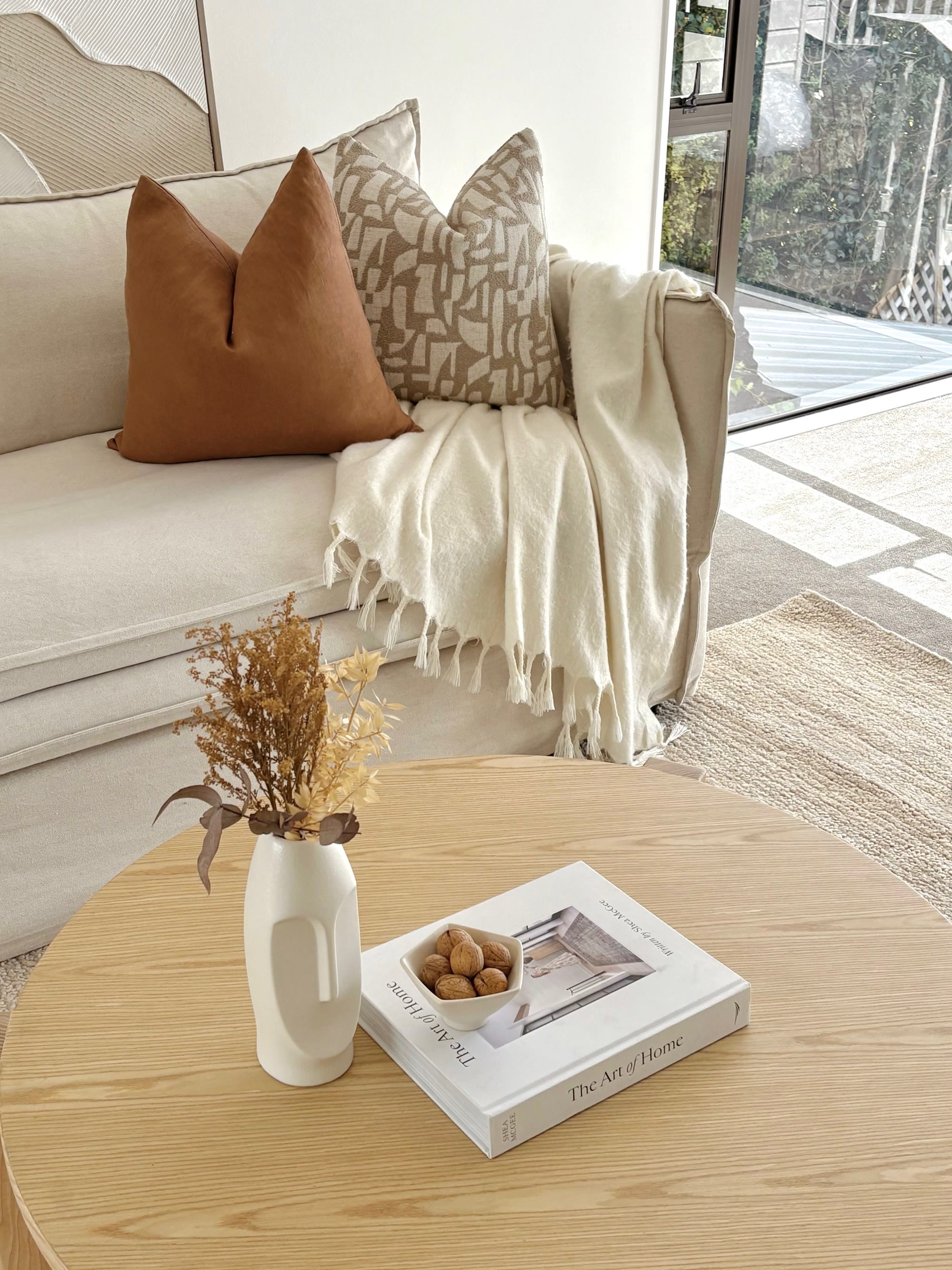 Lounge detail with caramel and patterned cushions, a cream throw and a pale timber coffee table